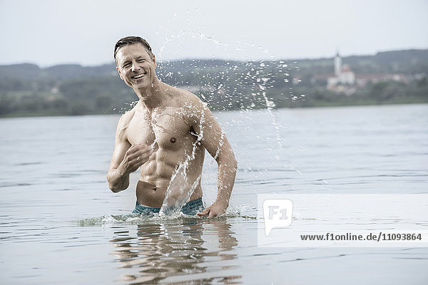 Mature man in lake with full of splash  Bavaria  Germany