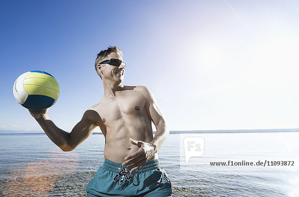 Mature man playing volleyball at the lakeside  Bavaria  Germany