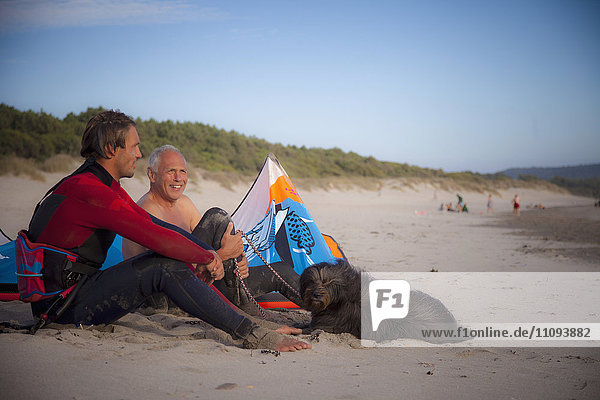 Kite surfer with his father sitting on the beach