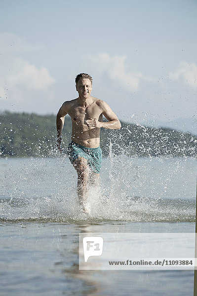 Mature man running through water at the lake  Bavaria  Germany