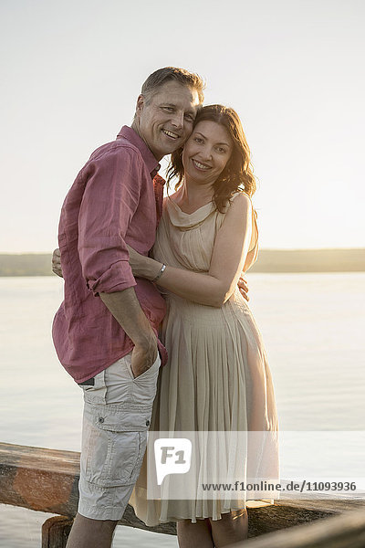 Porträt eines lächelnden reifen Paares auf einem Steg am See  Bayern  Deutschland