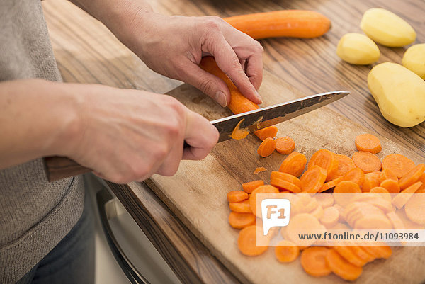 Frau schneidet Karotten auf einem Schneidebrett in der Küche