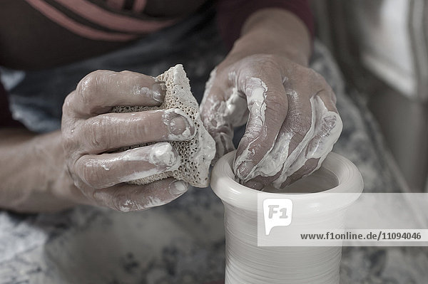Nahaufnahme einer Töpferin beim Formen von Ton mit einem Reinigungsschwamm in einer Werkstatt  Bayern  Deutschland