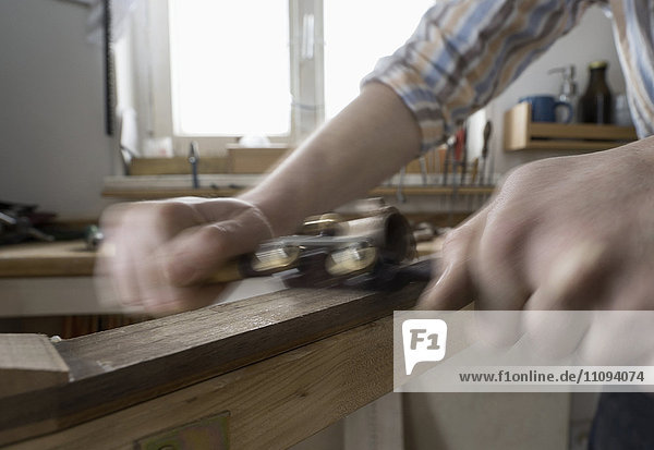 Männlicher Bogenbauer  der Holz spaltet und es in Form eines Bogens bringt  in einer Werkstatt  Bayern  Deutschland