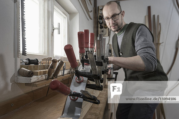 Männlicher Bogenbauer  der in einer Werkstatt Holz in Bogenform bringt  Bayern  Deutschland
