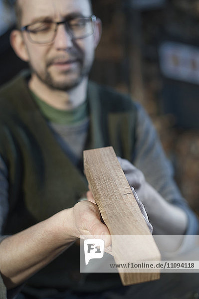 Männlicher Bogenbauer prüft die Qualität des Holzes in der Werkstatt  Bayern  Deutschland
