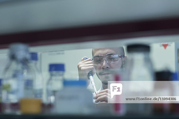 Wissenschaftler  der eine Probe in ein Reagenzglas im Forschungslabor pipettiert