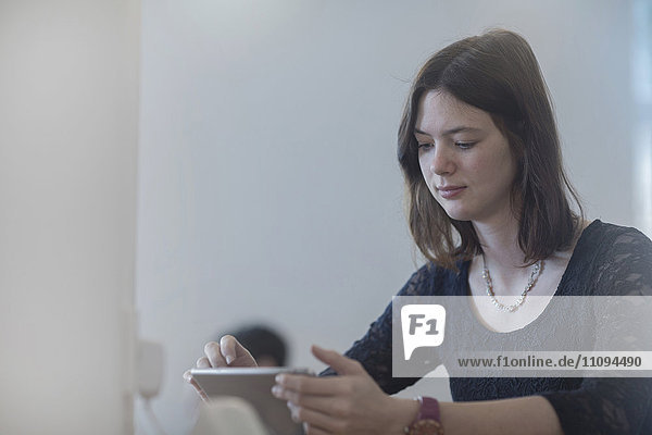 Geschäftsfrau bei der Arbeit an einem digitalen Tablet in einem Büro