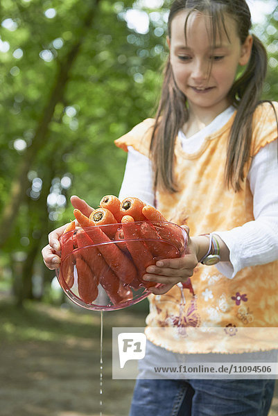 Mädchen hält Teller mit gewaschenen Möhren beim Picknick,  München,  Bayern,  Deutschland