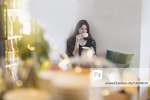 Junge Frau trinkt Kaffee in einem Kaffeehaus