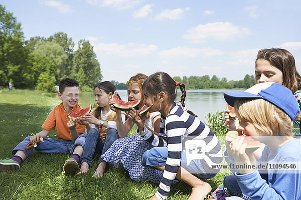Kinder genießen Scheiben von Wassermelonen beim Picknick  München  Bayern  Deutschland