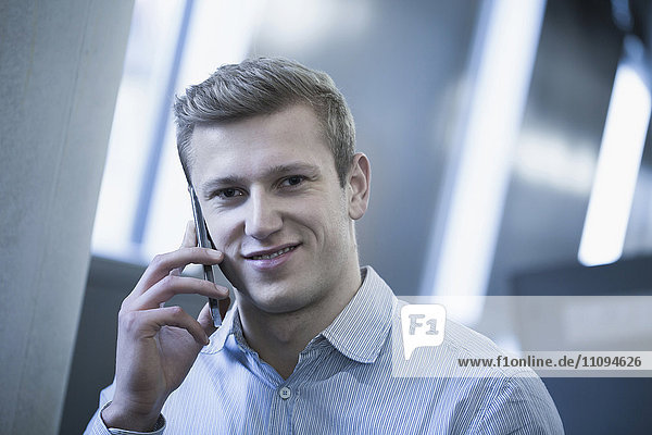 Portrait of young man talking on mobile phone in locker room
