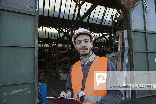 Porträt eines jungen männlichen Ingenieurs bei der Arbeit auf einer Baustelle