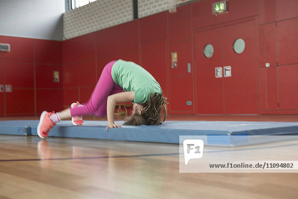 Mädchen macht Purzelbaum auf Übungsmatte in Sporthalle,  München,  Bayern,  Deutschland