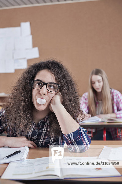 University student blowing bubblegum and thinking in classroom  Bavaria  Germany