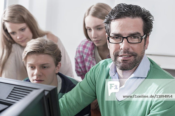 Teacher teaching students in computer lab  Bavaria  Germany