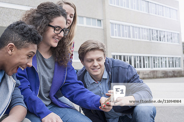 Universitätsstudenten  die sich mit ihrem Handy auf dem Campus vergnügen  Bayern  Deutschland