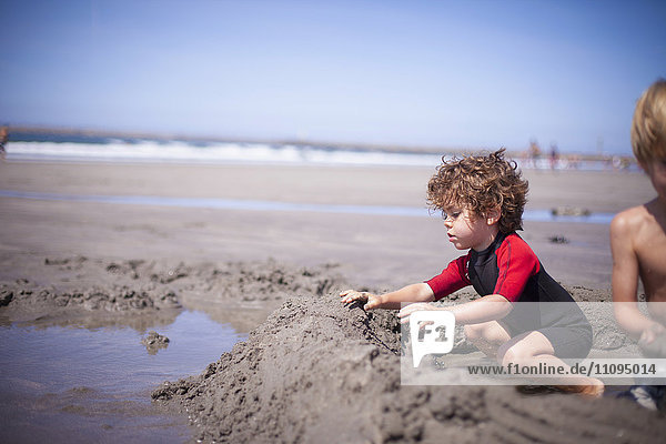 Zwei kleine Jungen bauen eine Sandburg im Sand am Strand  Viana do Castelo  Region Norte  Portugal