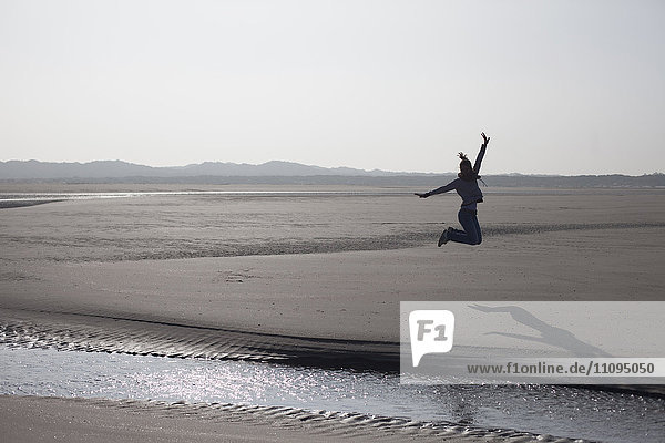 Mid adult woman jumping in mid-air on beach  Renesse  Schouwen-Duiveland  Zeeland  Netherlands