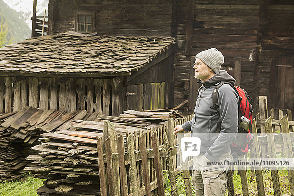 Älterer Wanderer in der Nähe einer Hütte an einem regnerischen Tag  Österreichische Alpen  Kärnten  Österreich