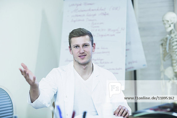 Portrait of a young doctor explaining about skeleton in his office  Freiburg Im Breisgau  Baden-Württemberg  Germany