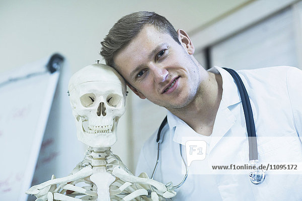 Porträt eines jungen Arztes mit Skelett in einer Arztpraxis  Freiburg im Breisgau  Baden-Württemberg  Deutschland