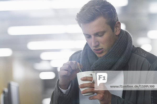 Junger Geschäftsmann trinkt Kaffee und arbeitet bis spät in die Nacht im Büro  Freiburg im Breisgau  Baden-Württemberg  Deutschland