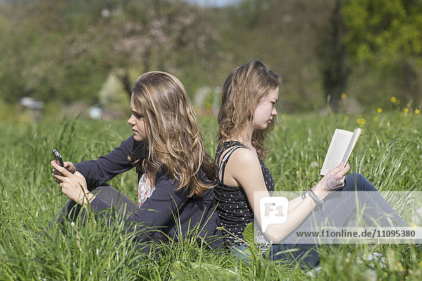 Teenage girls sitting in field Freiburg im Breisgau Baden-Württemberg Germany