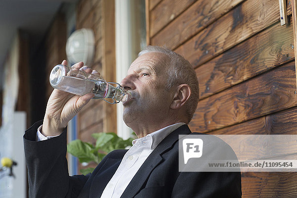 Älterer Geschäftsmann trinkt Wasser aus einer Flasche  Freiburg im Breisgau  Baden-Württemberg  Deutschland