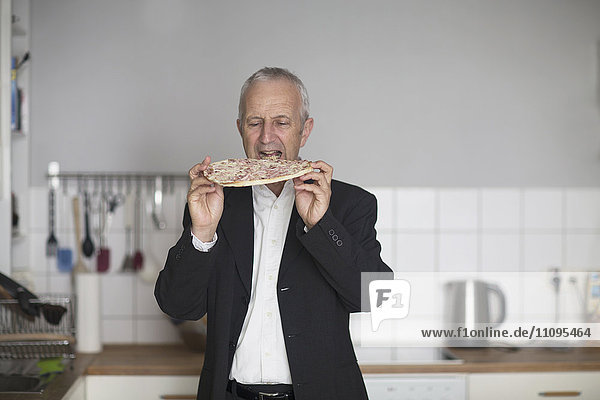 Älterer Geschäftsmann beim Pizzabacken in der Küche  Freiburg im Breisgau  Baden-Württemberg  Deutschland