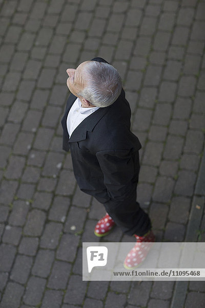 Älterer Geschäftsmann in Anzug und Gummistiefeln steht auf der Straße  Freiburg im Breisgau  Baden-Württemberg  Deutschland