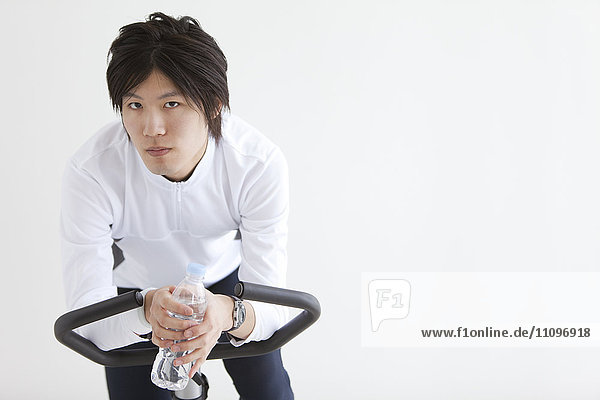 Young Man Leaning on Exercise Bike