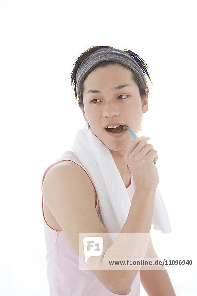 Junger Mann mit Stirnband beim Zähneputzen
