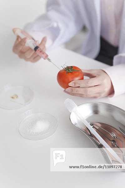 Young Woman Injecting Tomato