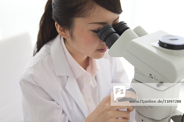 Junge Wissenschaftlerin mit Mikroskop im Labor