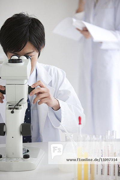 Young Male Scientist Using Microscope in Laboratory