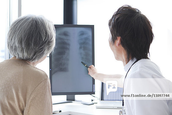 Doctor Looking at X-Ray with Senior Woman