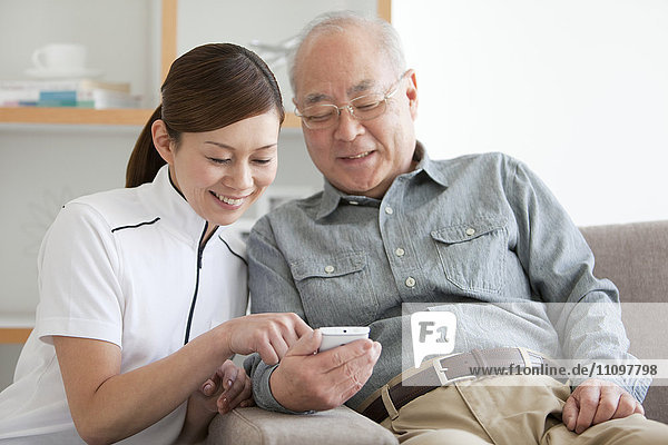 Senior Male Patient and Nurse Looking at Mobile Phone