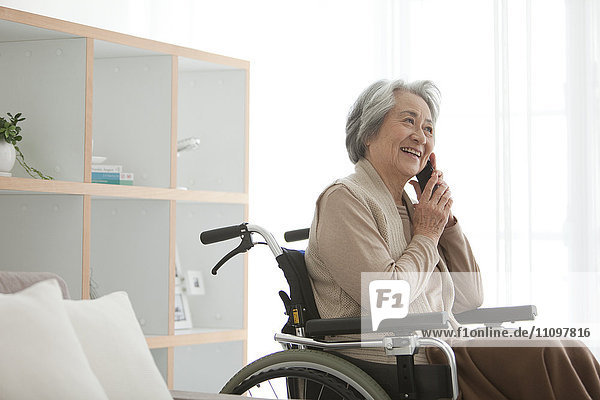 Ältere Frau im Rollstuhl benutzt Telefon