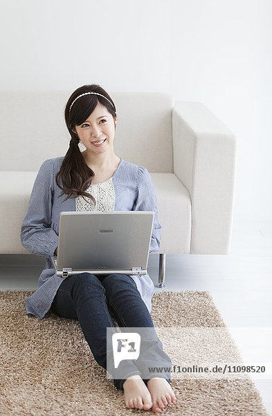 Young Woman Using Laptop on Living Room Floor
