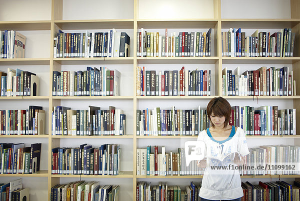 Female student reading book at library