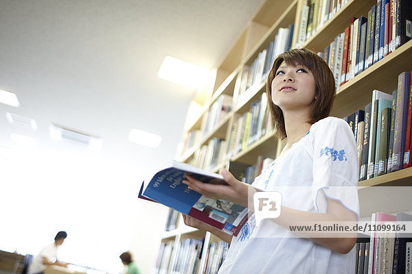 Studentin liest ein Buch in der Bibliothek