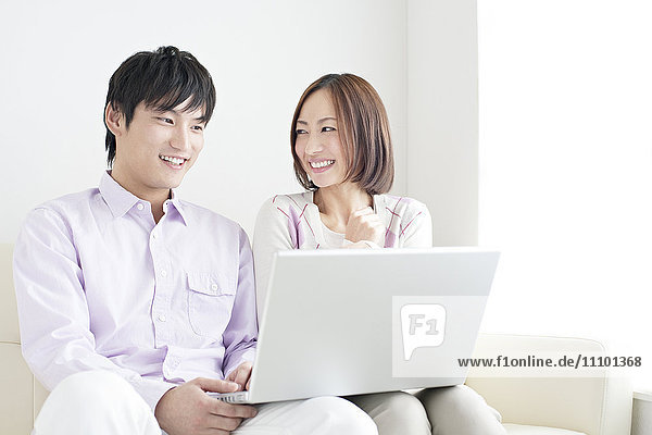 Young couple sitting on sofa using laptop