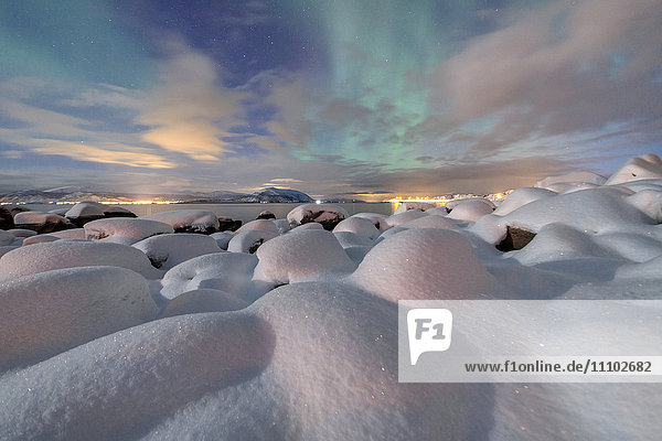 Das rosafarbene Licht und die Aurora borealis (Nordlichter) erhellen die Schneelandschaft in einer sternenklaren Nacht Stronstad  Lofoten  Arktis  Norwegen Skandinavien  Europa