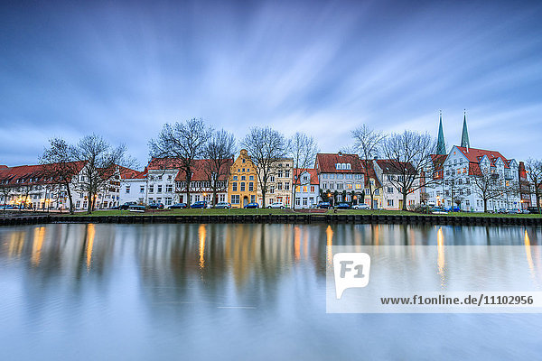 Wolken auf den typischen Häusern und Türmen des Doms spiegeln sich in der Trave in der Abenddämmerung  Lübeck  Schleswig Holstein  Deutschland  Europa