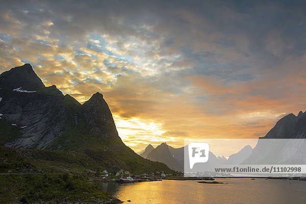 Sonnenuntergang auf dem Fischerdorf  umgeben von felsigen Gipfeln und Meer  Reine  Landkreis Nordland  Lofoten  Arktis  Nordnorwegen  Skandinavien  Europa