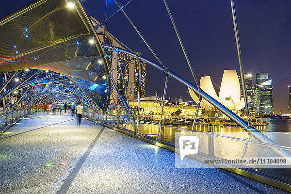 People strolling on the Helix Bridge towards the Marina Bay Sands and ArtScience Museum at night  Marina Bay  Singapore  Southeast Asia  Asia