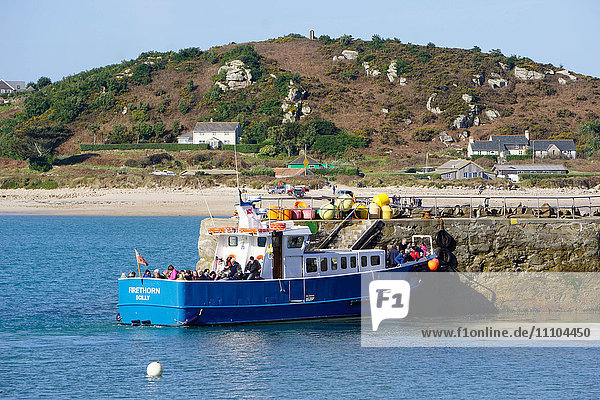 Travellers boarding boat at New Grimsby Quay on Tresco with Bryher in background  Isles of Scilly  England  United Kingdom  Europe