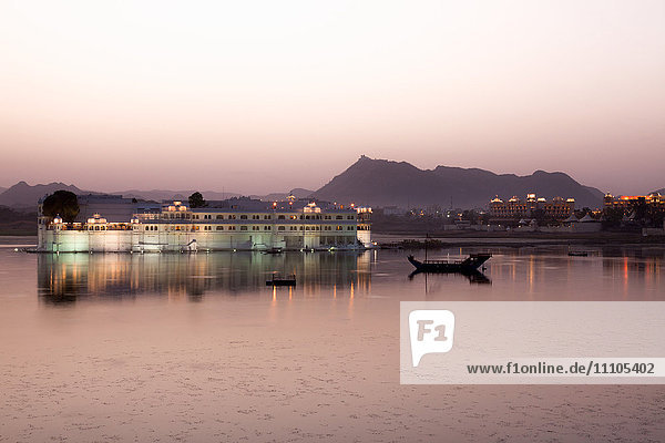 Perfekte Spiegelung des Lake Palace Hotel in der Abenddämmerung  inmitten des Pichola-Sees  in Udaipur  Rajasthan  Indien  Asien