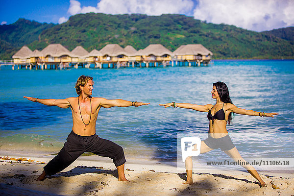 Paar beim Yoga vor den Überwasserbungalows  Le Taha'a Resort  Tahiti  Französisch-Polynesien  Südpazifik  Pazifik